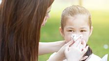 allergy_mother_and_little_girl_blowing_nose_at_outside_in_the-park_small